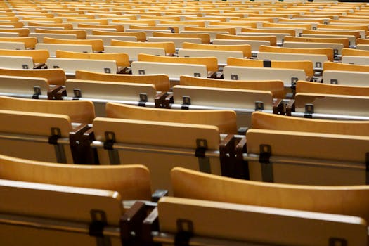 Image of empty wooden seats in an academic auditorium, located indoors.